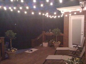 A deck with lights and chairs on it