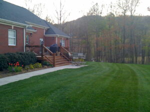 A large yard with a house and trees in the background.