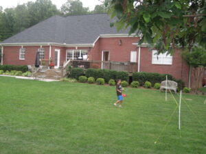 A young boy is playing frisbee in the yard.