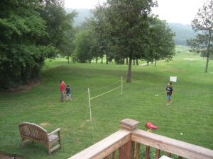 A group of people playing tennis on the grass.