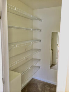 A white room with shelves and mirror in it.