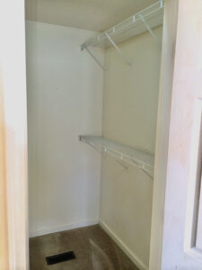 A closet with two shelves and a door.