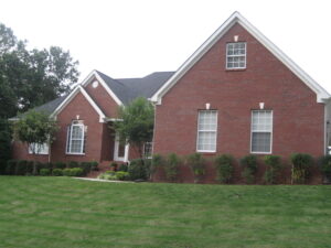 A large brick house with green grass in front of it.