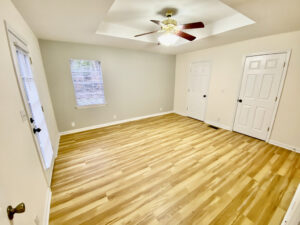 A room with hard wood floors and ceiling fan.