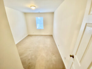 A room with white walls and beige carpet.