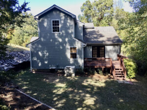 A house with a deck and steps in the yard.