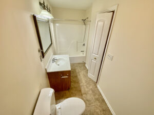 A bathroom with a toilet, sink and mirror.