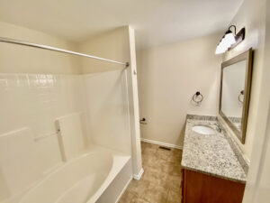 A bathroom with a tub, sink and mirror.