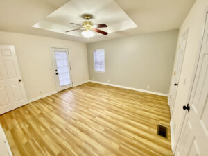 A room with hard wood floors and ceiling fan.