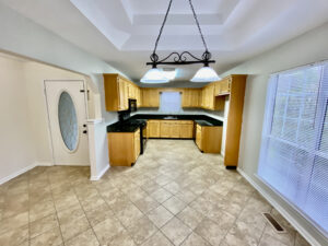 A kitchen with tile floors and wooden cabinets.