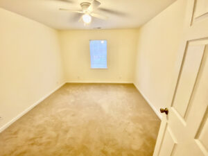 A bedroom with a window and ceiling fan.