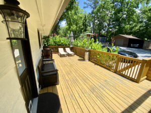 A wooden deck with chairs and trees in the background.