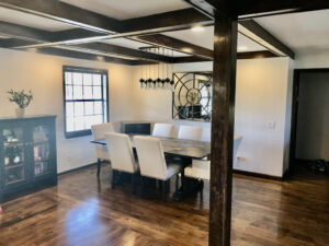 A dining room with wooden floors and white chairs.