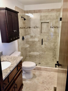 A bathroom with marble tile and granite counter tops.