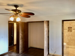 A room with a ceiling fan and wooden floors.