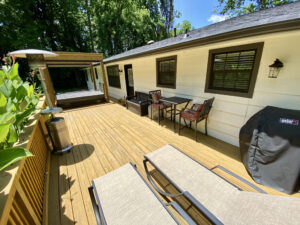 A deck with chairs and tables outside of the house