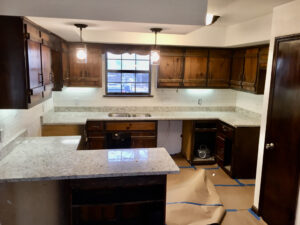 A kitchen with brown cabinets and white counter tops.