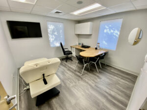 A room with two chairs, a desk and a television.