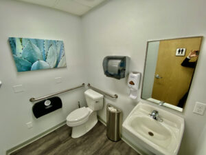 A bathroom with a toilet, sink and mirror.