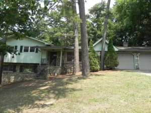 A house with trees in the background and grass on the ground.