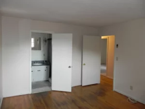 A room with two doors open and a sink in the corner.