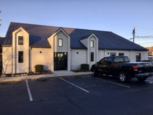 A car parked in front of a building with a large window.