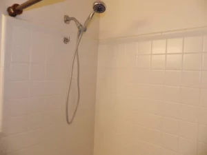 A shower head hanging in the corner of a bathroom.