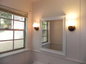 A bathroom with a large mirror and two lights.