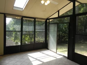 A room with a ceiling fan and glass windows.