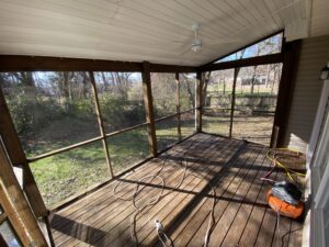 A porch with wood floors and a screen door.