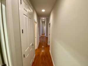 A hallway with two doors and wooden floors.