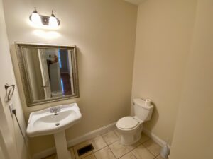 A bathroom with a sink, toilet and mirror.