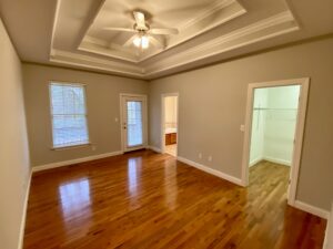 A room with hard wood floors and ceiling fan.