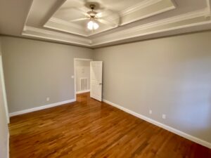 A room with hard wood floors and ceiling fan.