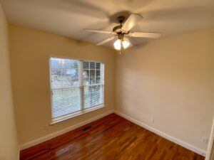 A room with a ceiling fan and wooden floors.