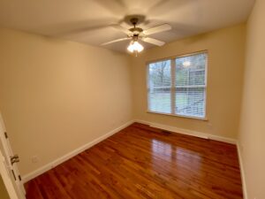 A room with hard wood floors and ceiling fan.