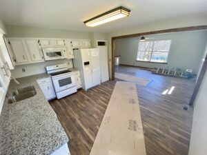 A kitchen with hard wood floors and white appliances.