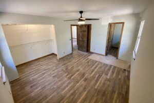 AN empty living room with wooden floor and a ceiling fan