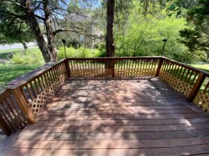 A wooden deck with chairs and trees in the background.