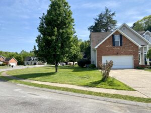 A house with a driveway and trees in the background