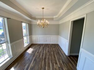 A dining room with white walls and wooden floors.