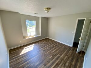 A room with hard wood floors and a window.