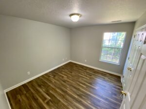 A room with hard wood floors and a window.