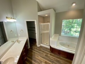 A bathroom with wood floors and white fixtures.