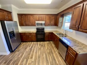 A kitchen with wooden cabinets and wood floors.