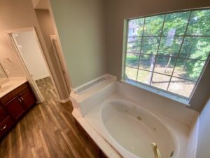 A bathroom with a tub and wooden floors