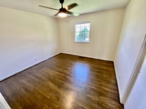 A room with hard wood floors and a ceiling fan.