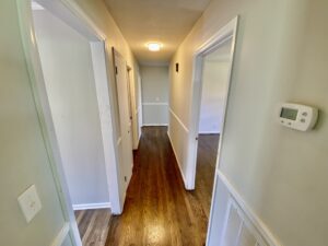 A hallway with two doors and wooden floors.