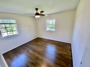 A bedroom with hard wood floors and ceiling fan.