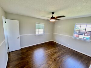 A room with hard wood floors and a ceiling fan.